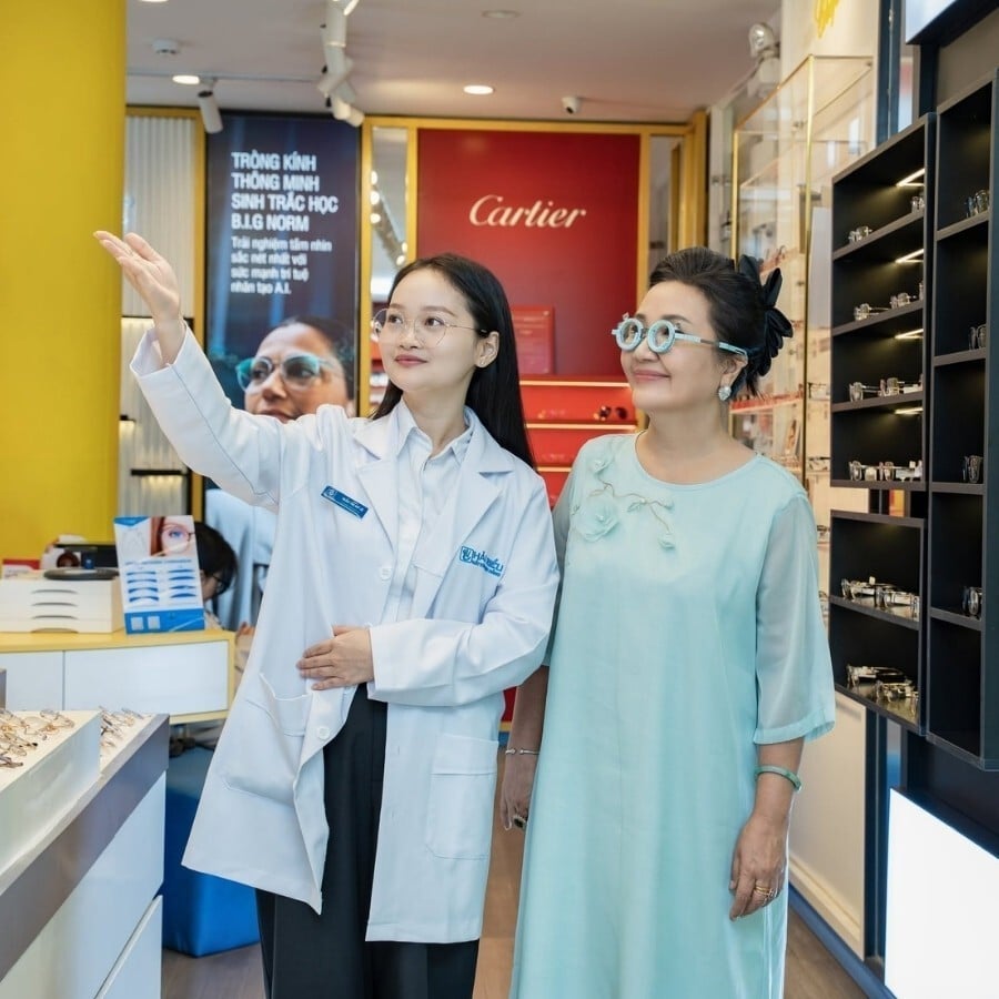 Kỹ thuật viên giúp khách đeo thử kính và đi lại quanh showroom
