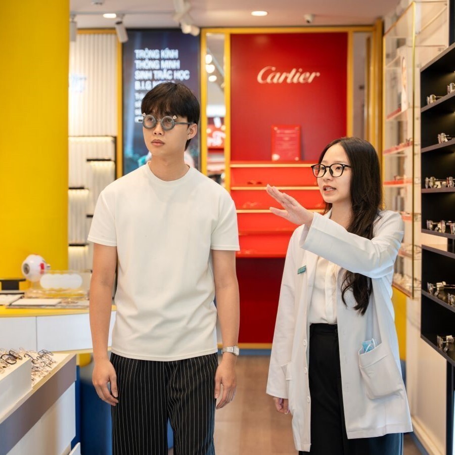 Kỹ thuật viên giúp khách đeo thử kính và đi lại quanh showroom