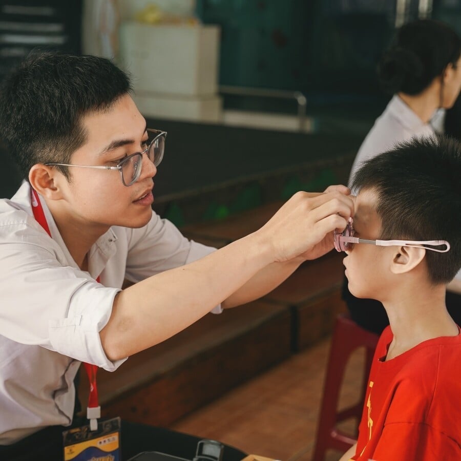 Kỹ thuật viên đang đo mắt cho bé trong dự án thiện nguyện