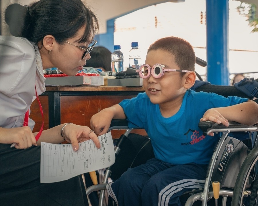 Kỹ thuật viên Hải Triều hỗ trợ thử kính cho bé tại Làng May Mắn